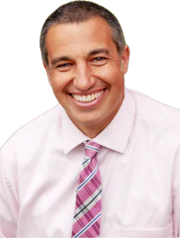 a smiling man in a pink shirt and tie